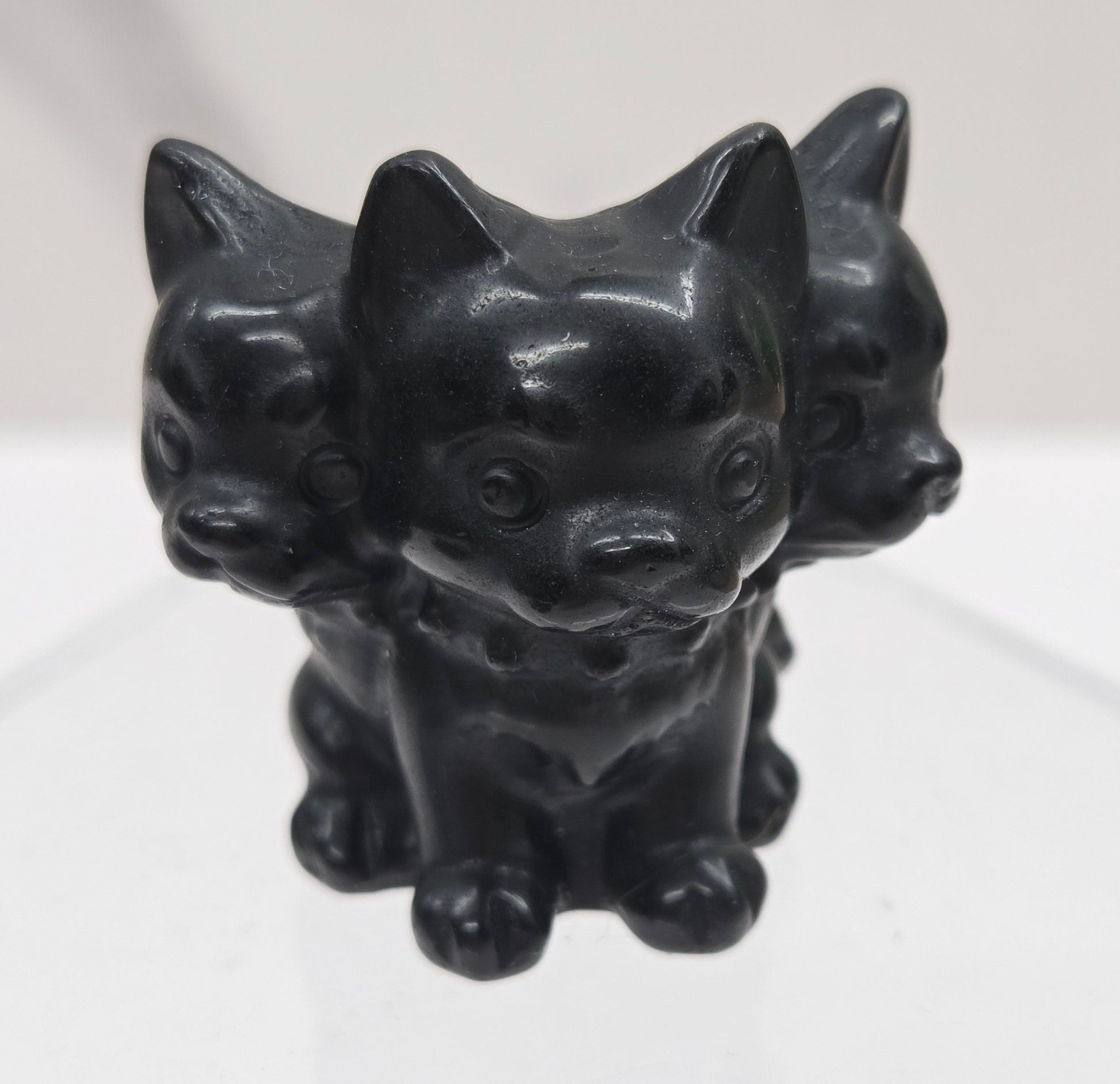 Obsidian small crystal mythological cerberus animal figurines on a white surface