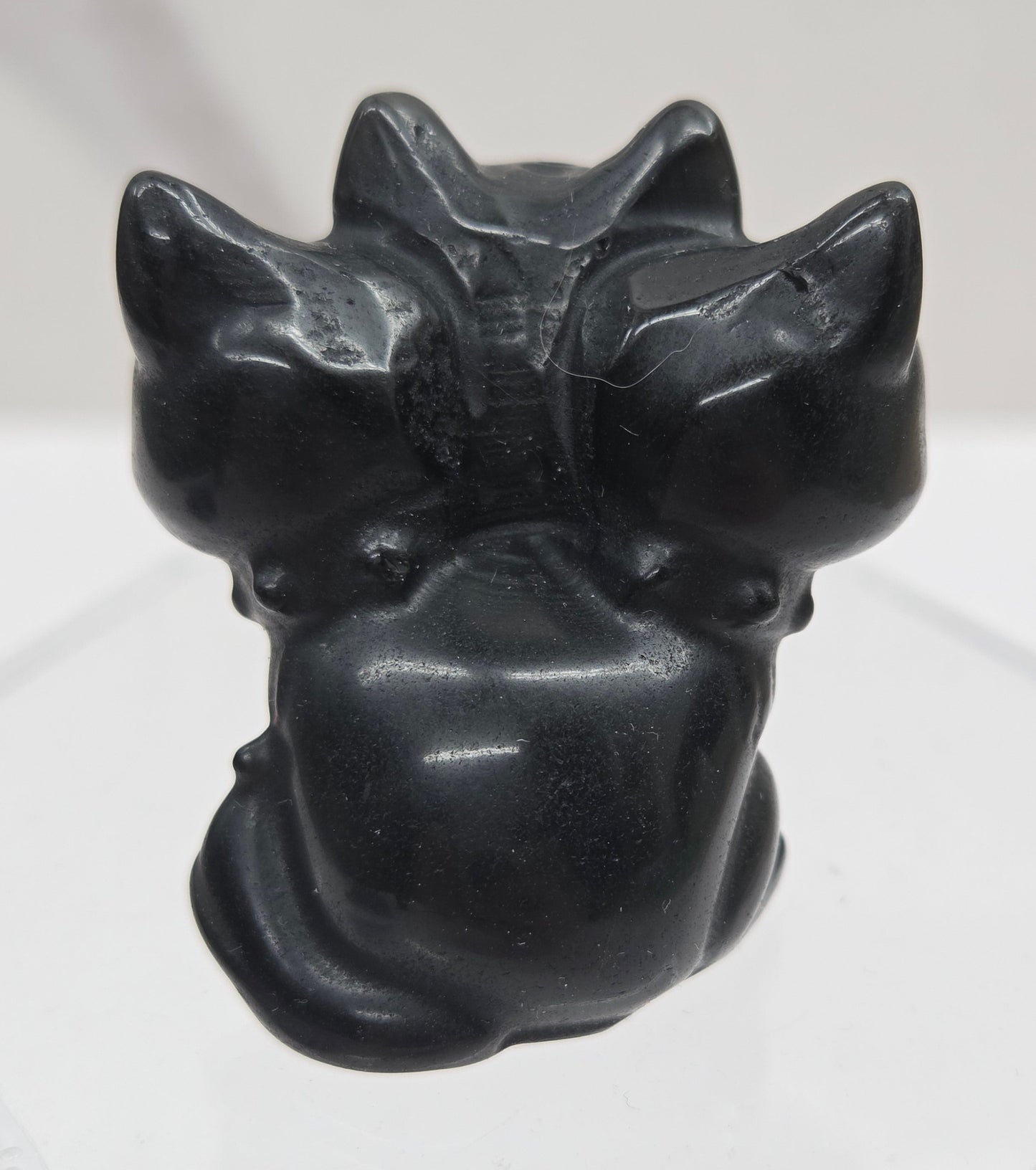 Obsidian small crystal mythological cerberus animal figurines on a white surface