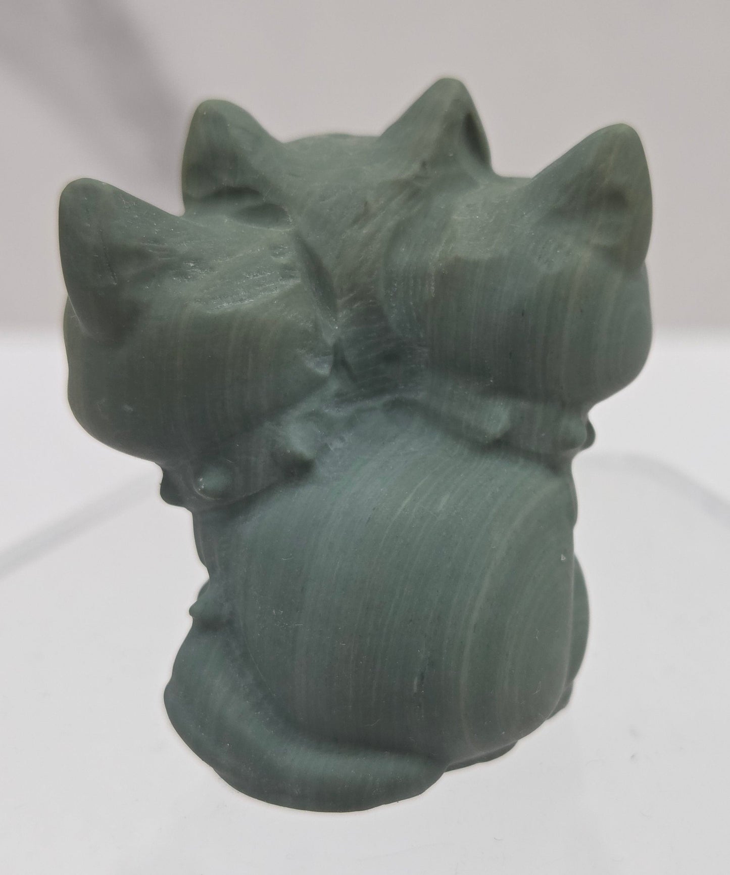 Green Jasper small crystal mythological cerberus animal figurines on a white surface