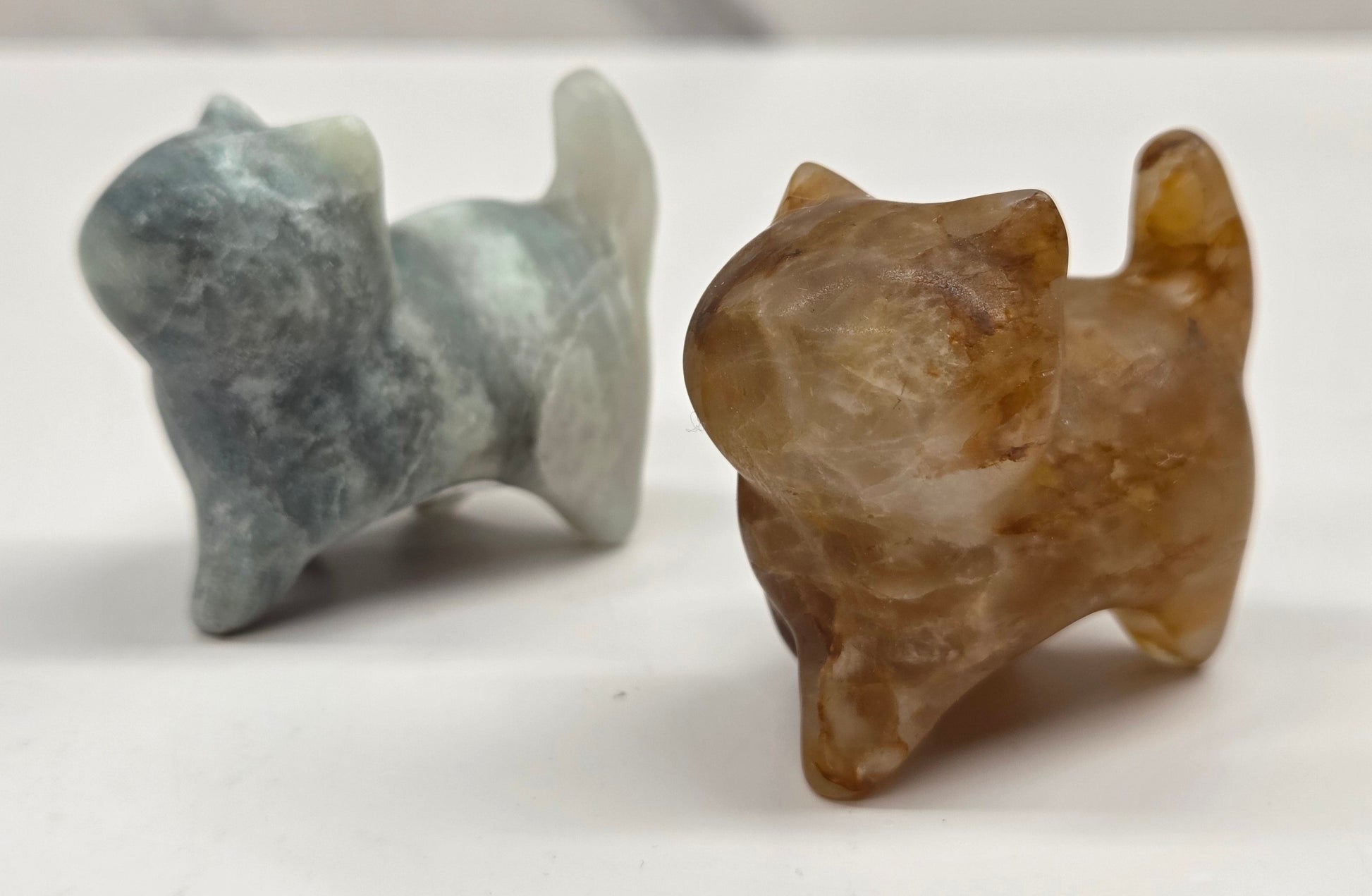 Two stone cat figurines on a white surface