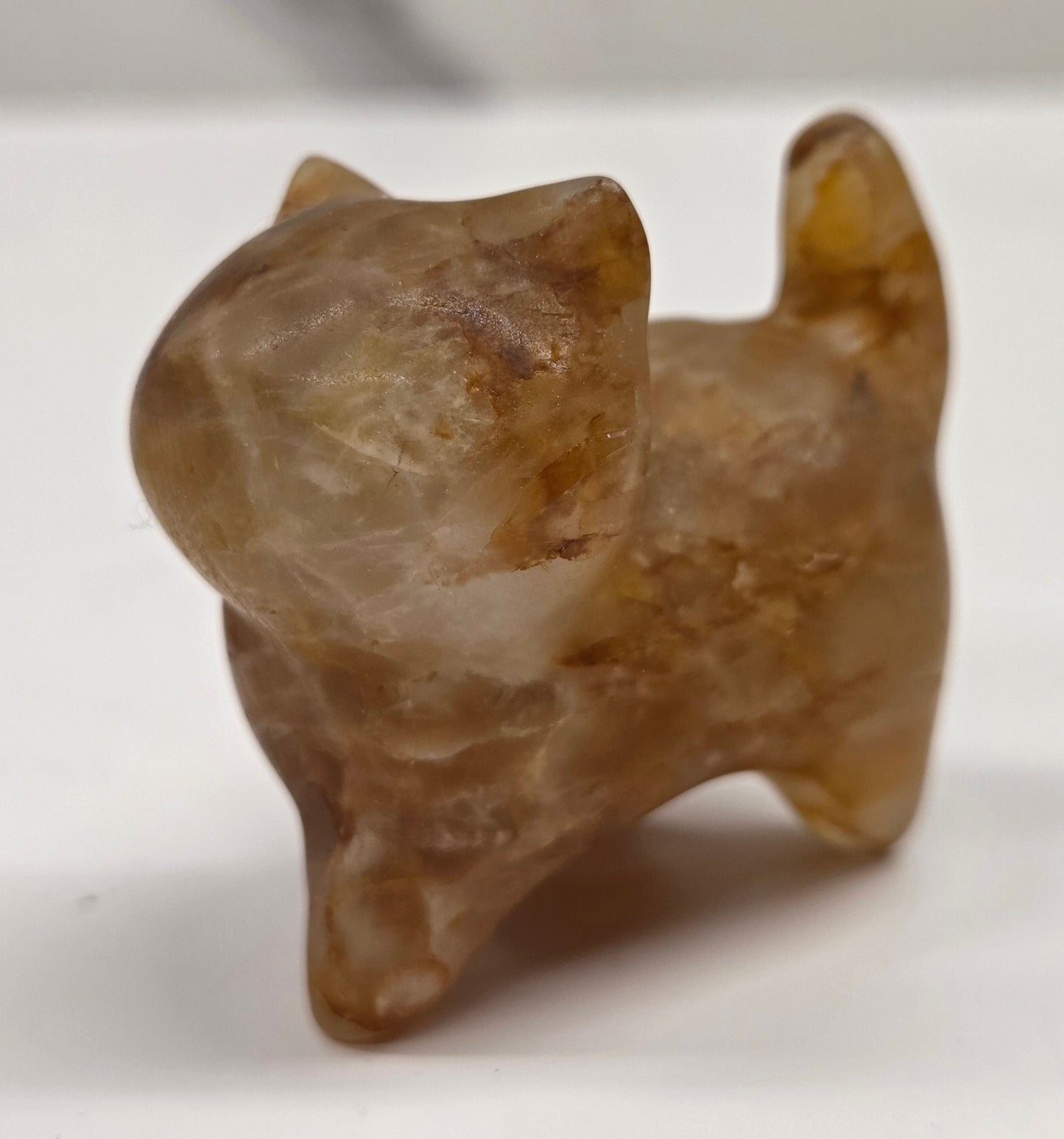 Small stone golden healer sculpture of a cat on a white background