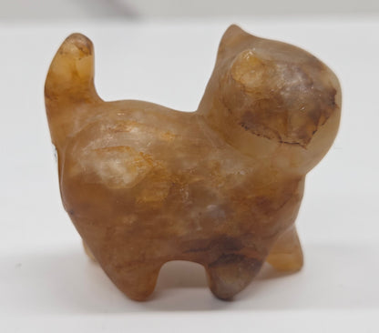 Small stone golden healer sculpture of a cat on a white background