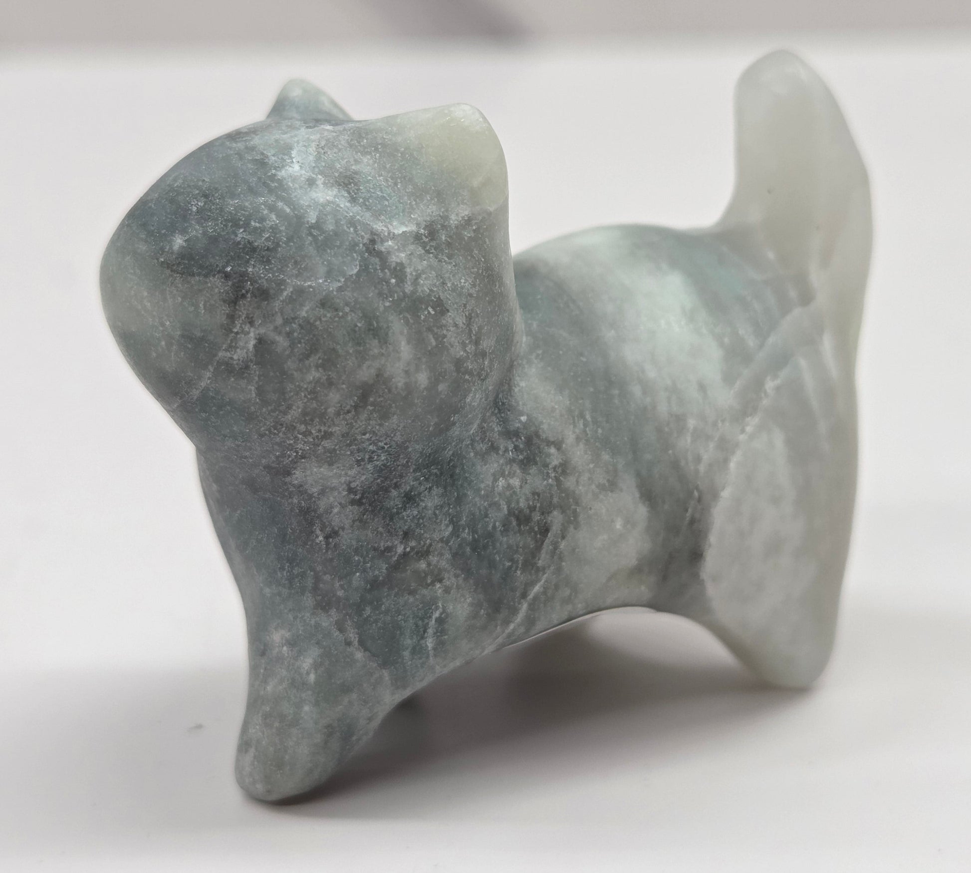 Small stone blue calcite sculpture of a cat on a white background
