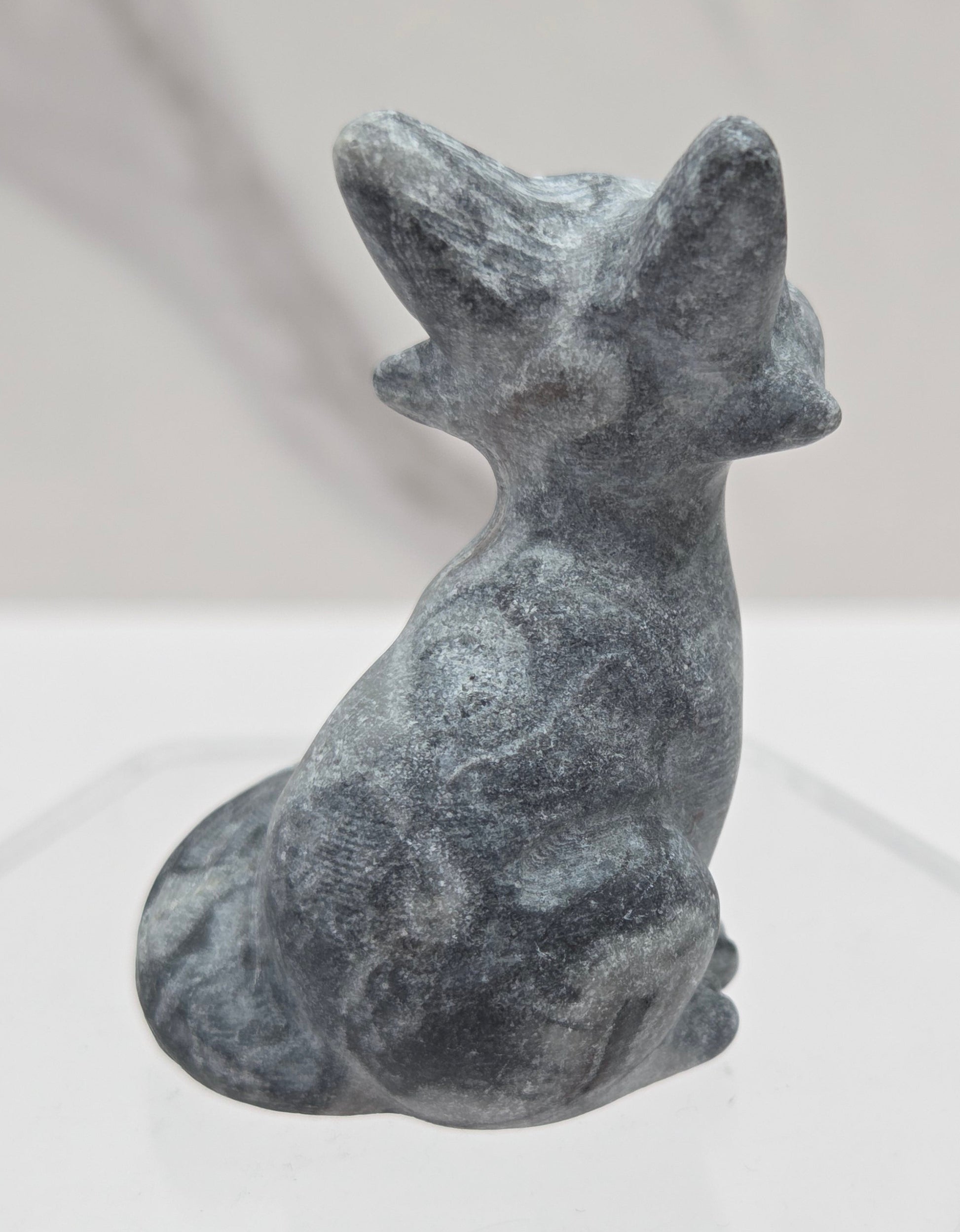 Fossil Shell Jasper fox carving with grey and black coloring on a white background