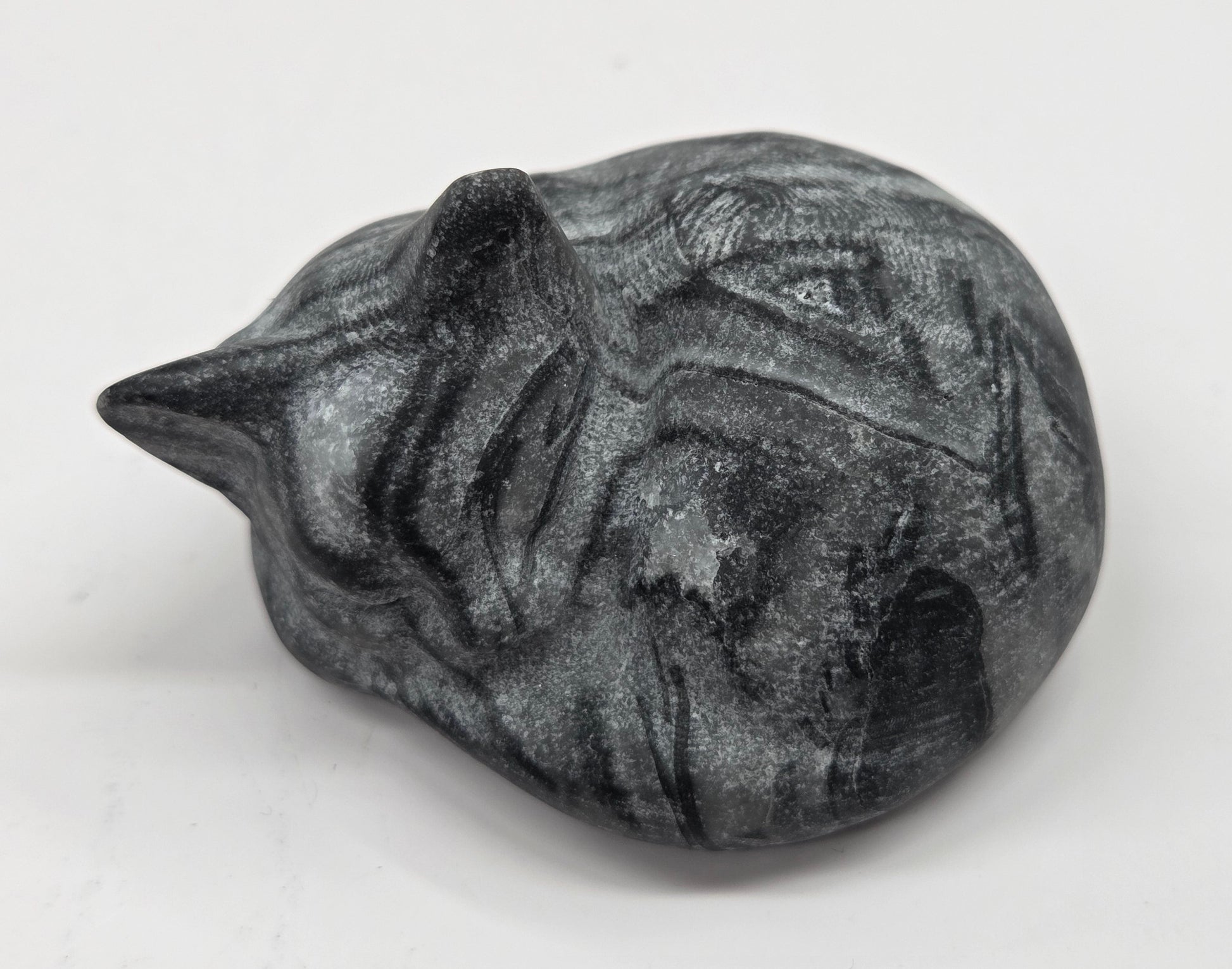 Fossil Shell Jasper sleeping cat carving with black and grey coloring on a white background
