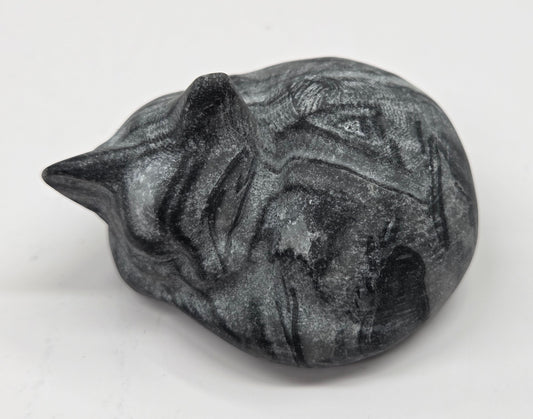 Fossil Shell Jasper sleeping cat carving with black and grey coloring on a white background