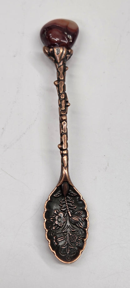 Slotted crystal-topped spoon with varying crystal attachments and decorative leaf-like patterns on the handles.