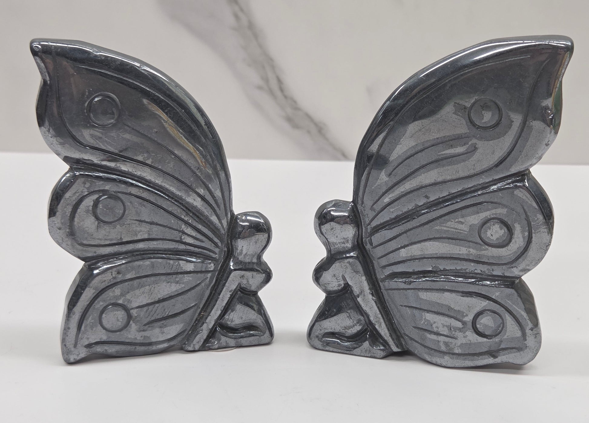 Silver hematite fairy carvings on a white background