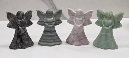 Four stone fairy figurines in different colors on a white surface with a marble background.