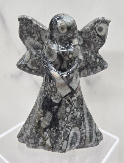 Crinoid fossil fairy figurine with visible fossils on a white background
