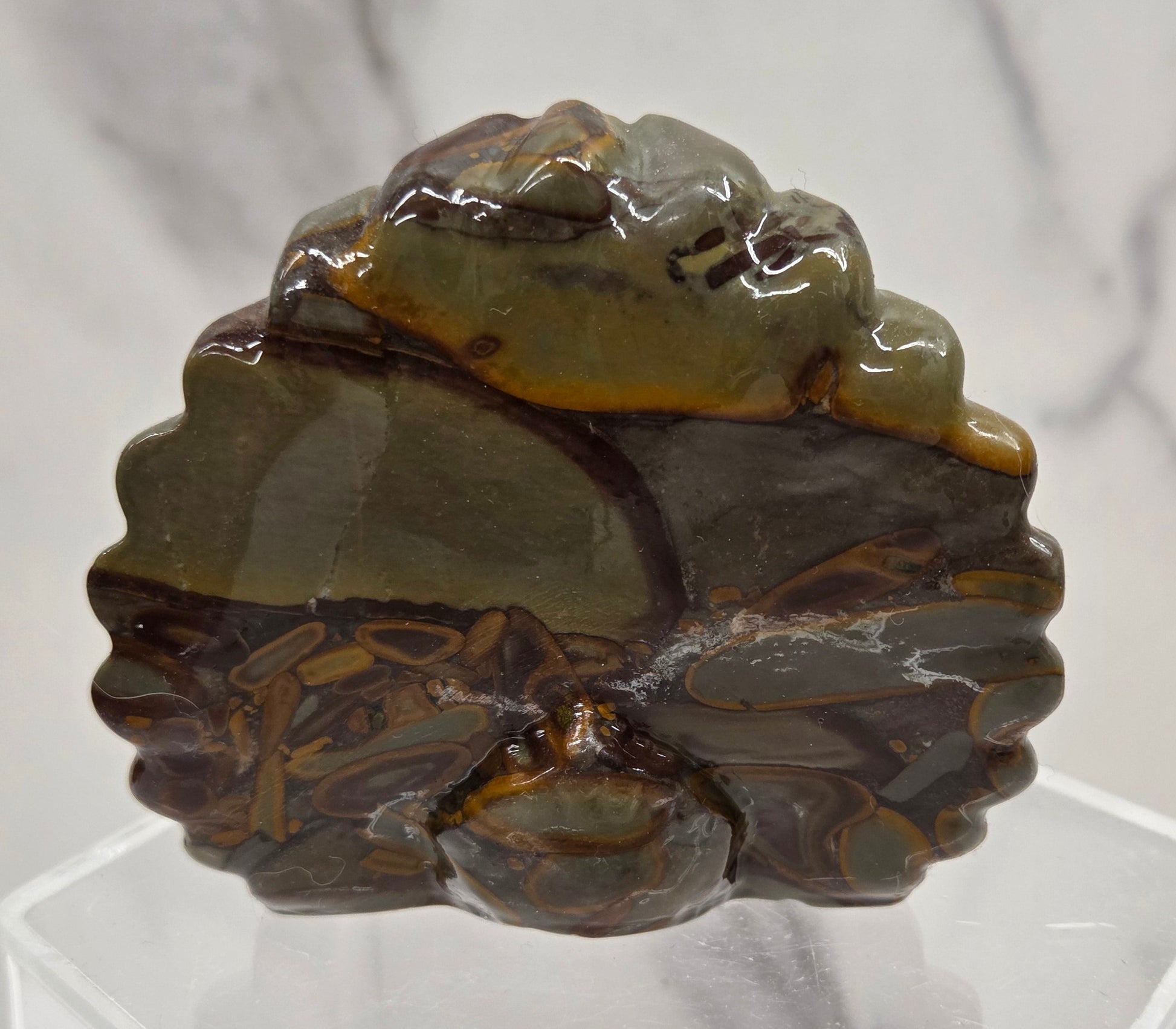 Decorative bamboo jasper peacock carving on a clear stand against a white background