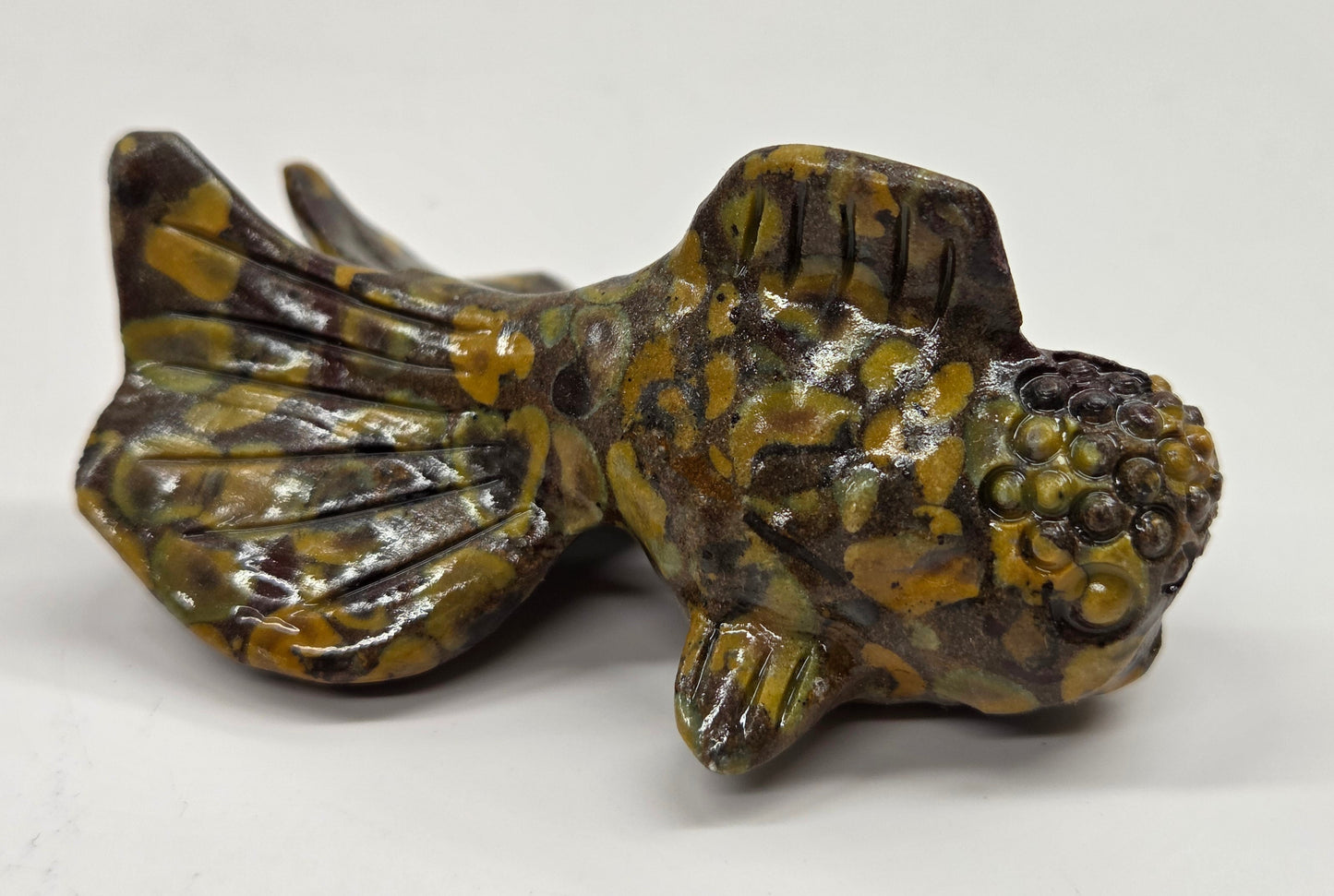 Colorful ajooba jasper fish figurine on a white background