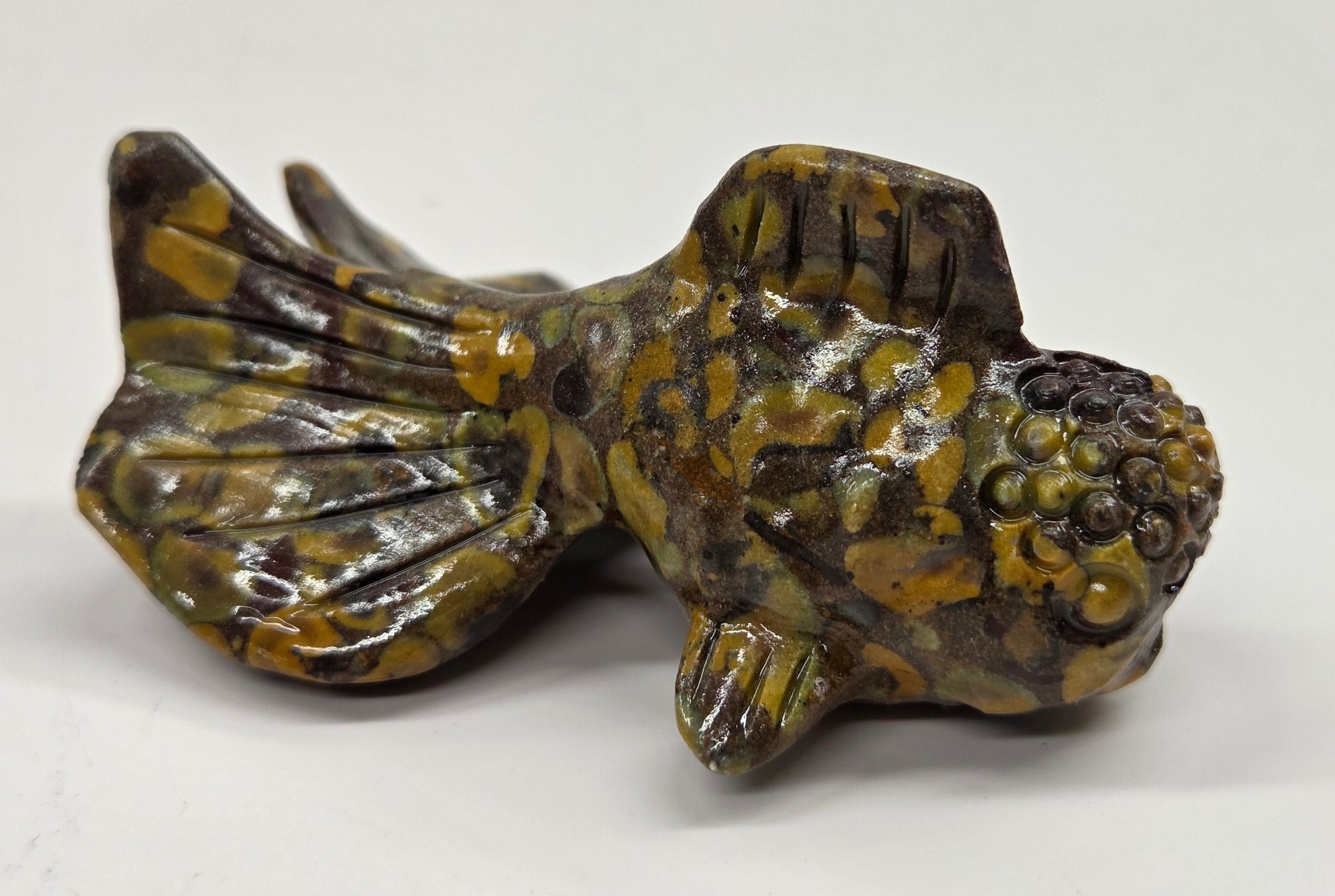 Colorful ajooba jasper fish figurine on a white background