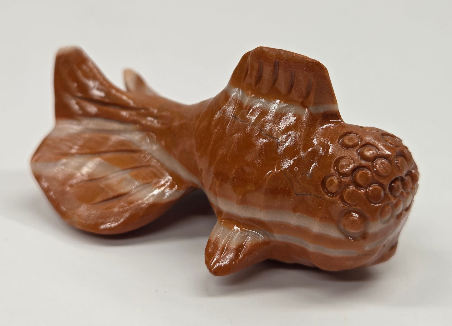 Red jasper fish figurine on a white background