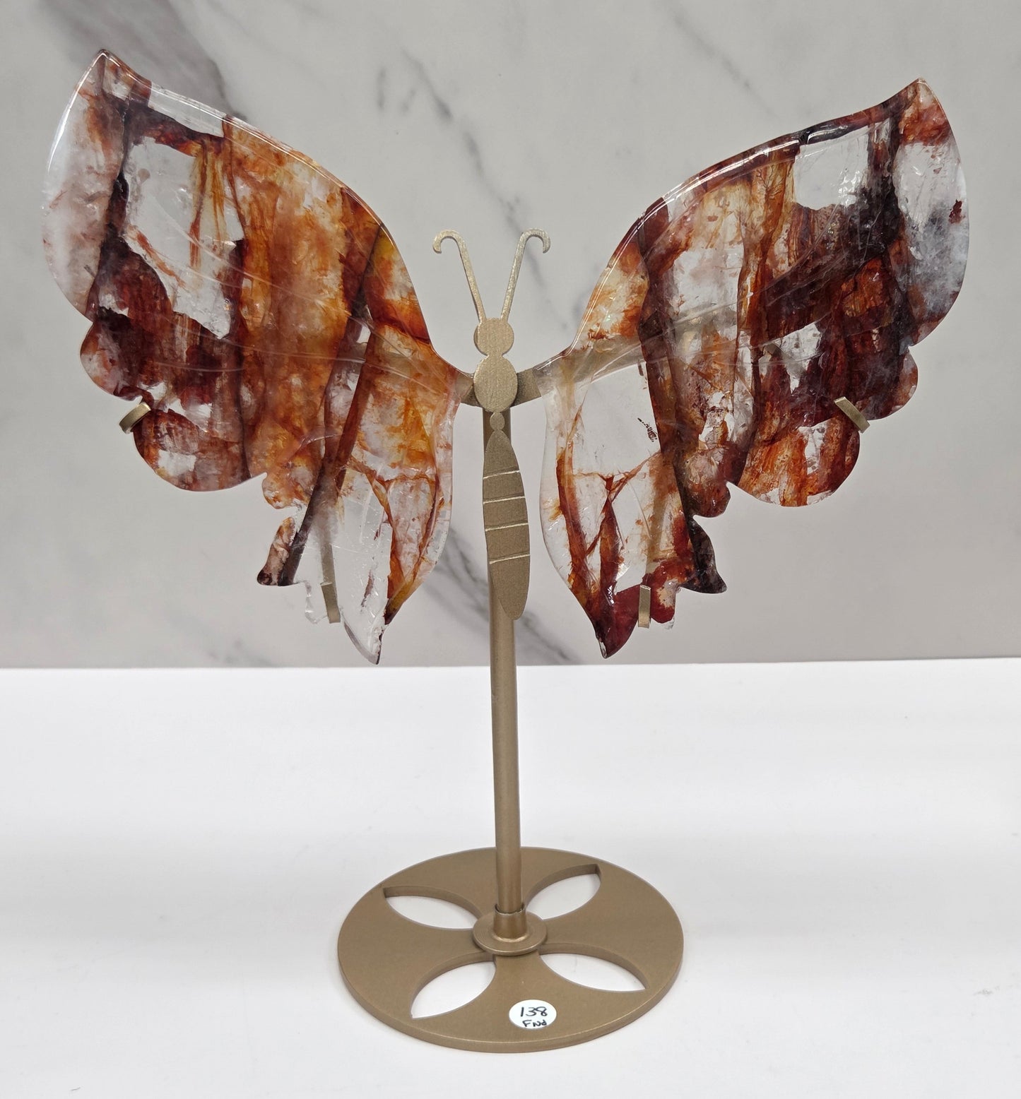 Fire Quartz butterfly wing carvings on a gold metal stand on a white background