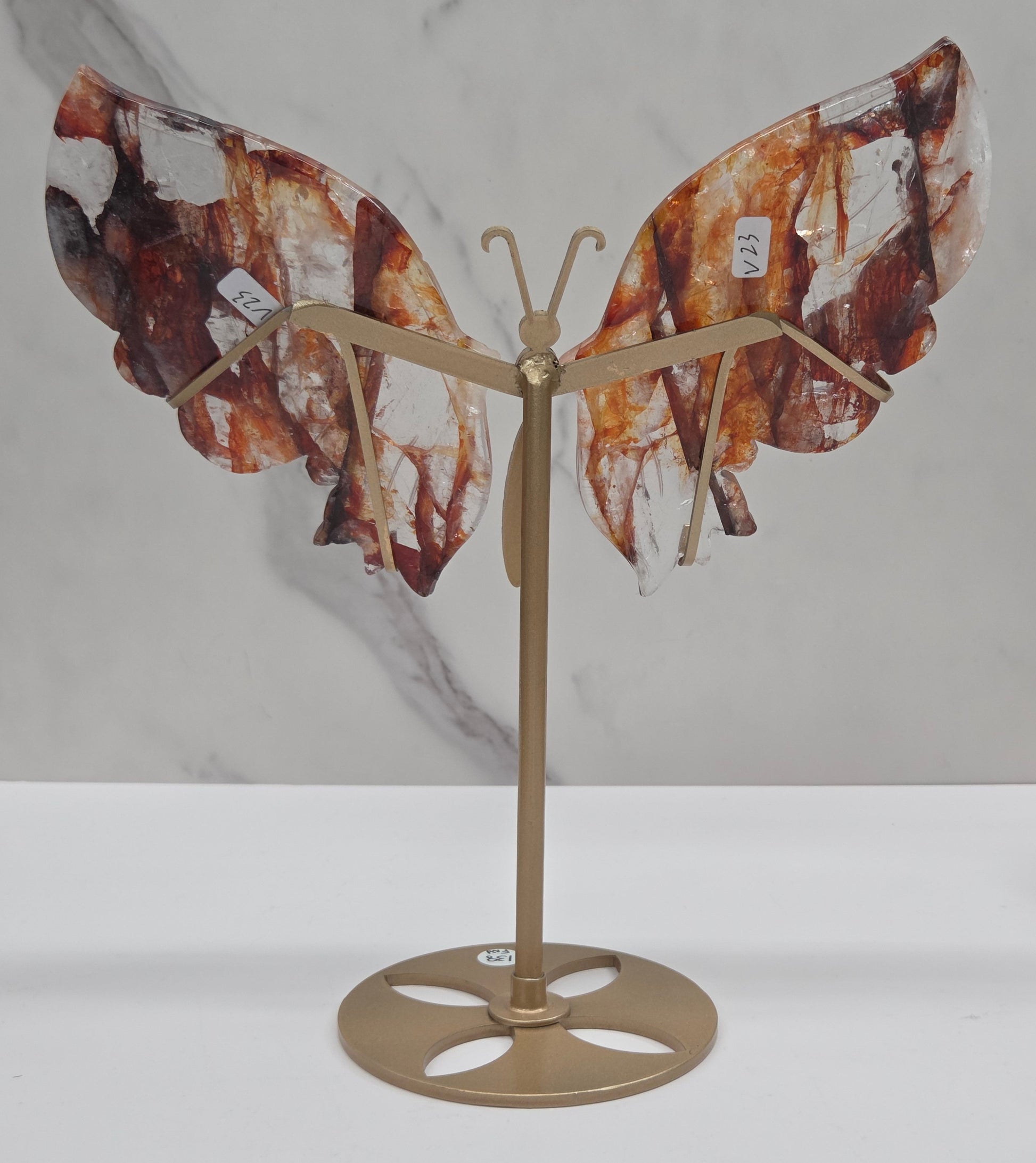 Fire Quartz butterfly wing carvings on a gold metal stand on a white background