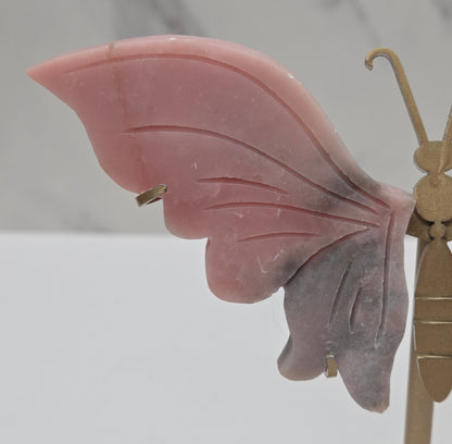 Pink Opal crystal wing carvings on a gold metal stand on a white background