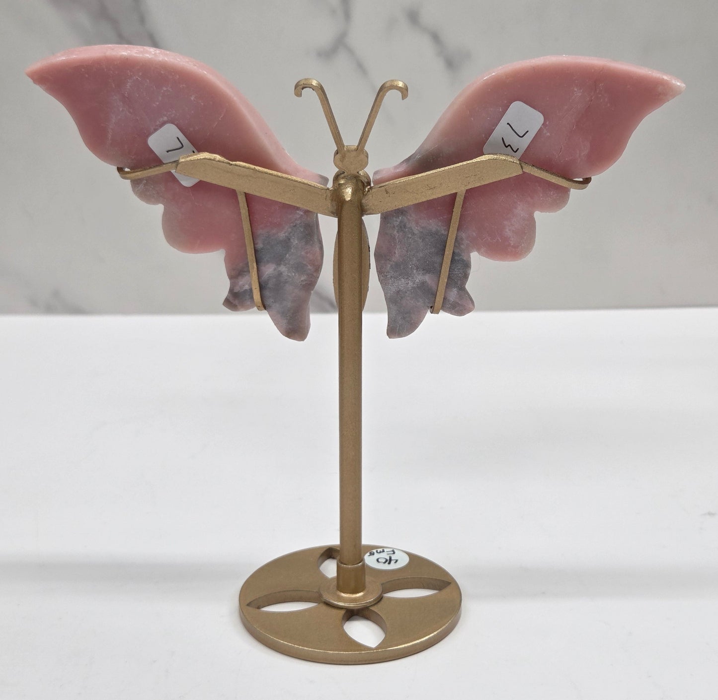 Pink Opal crystal wing carvings on a gold metal stand on a white background