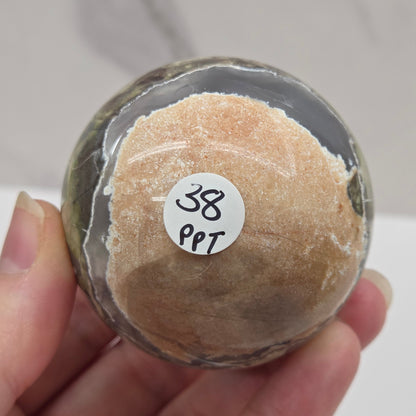 money agate multiple colored sphere held in a hand with a blurred background