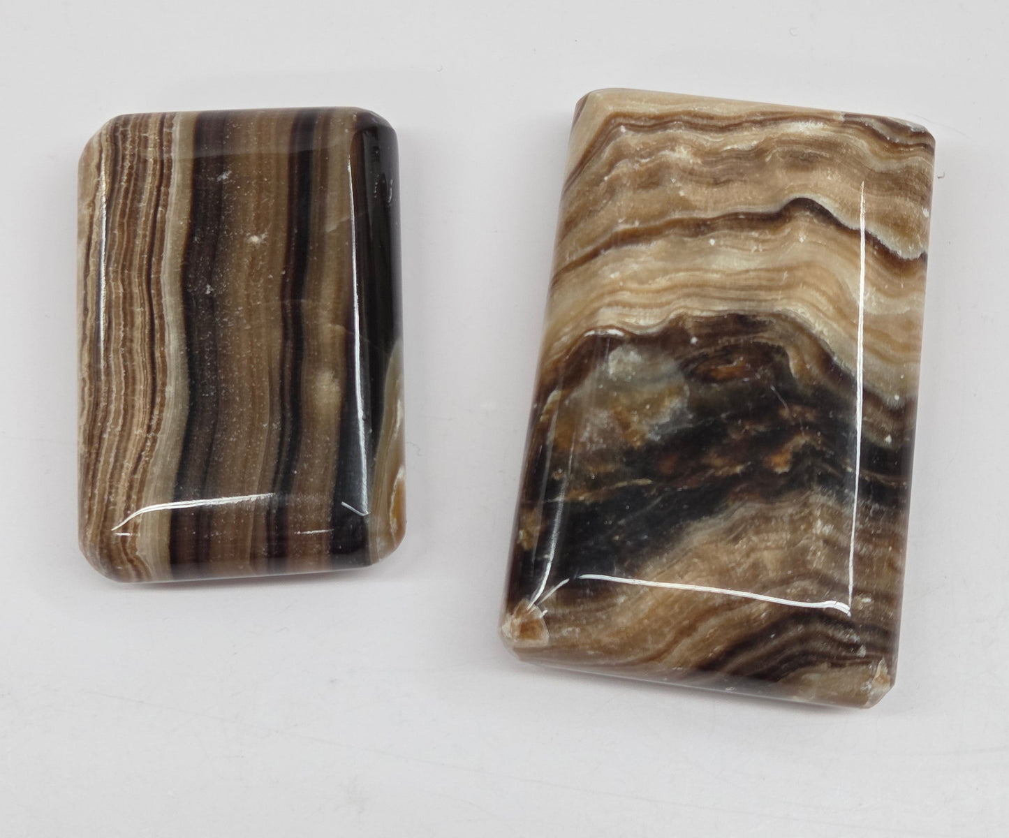 Two polished chocolate calcite soap shaped carvings on a white background