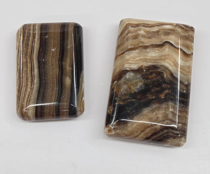 Two polished chocolate calcite soap shaped carvings on a white background