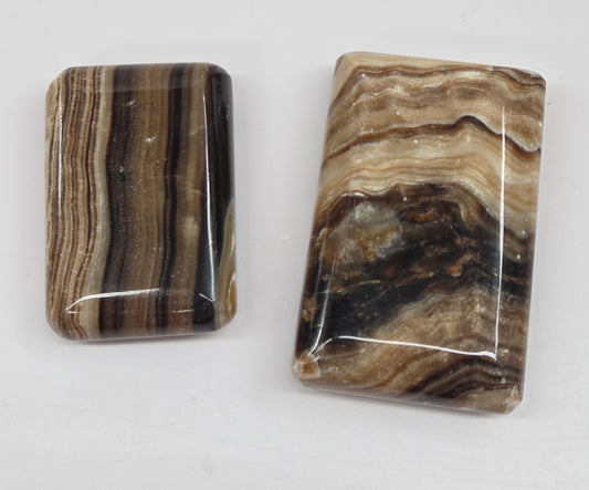 Two polished chocolate calcite soap shaped carvings on a white background