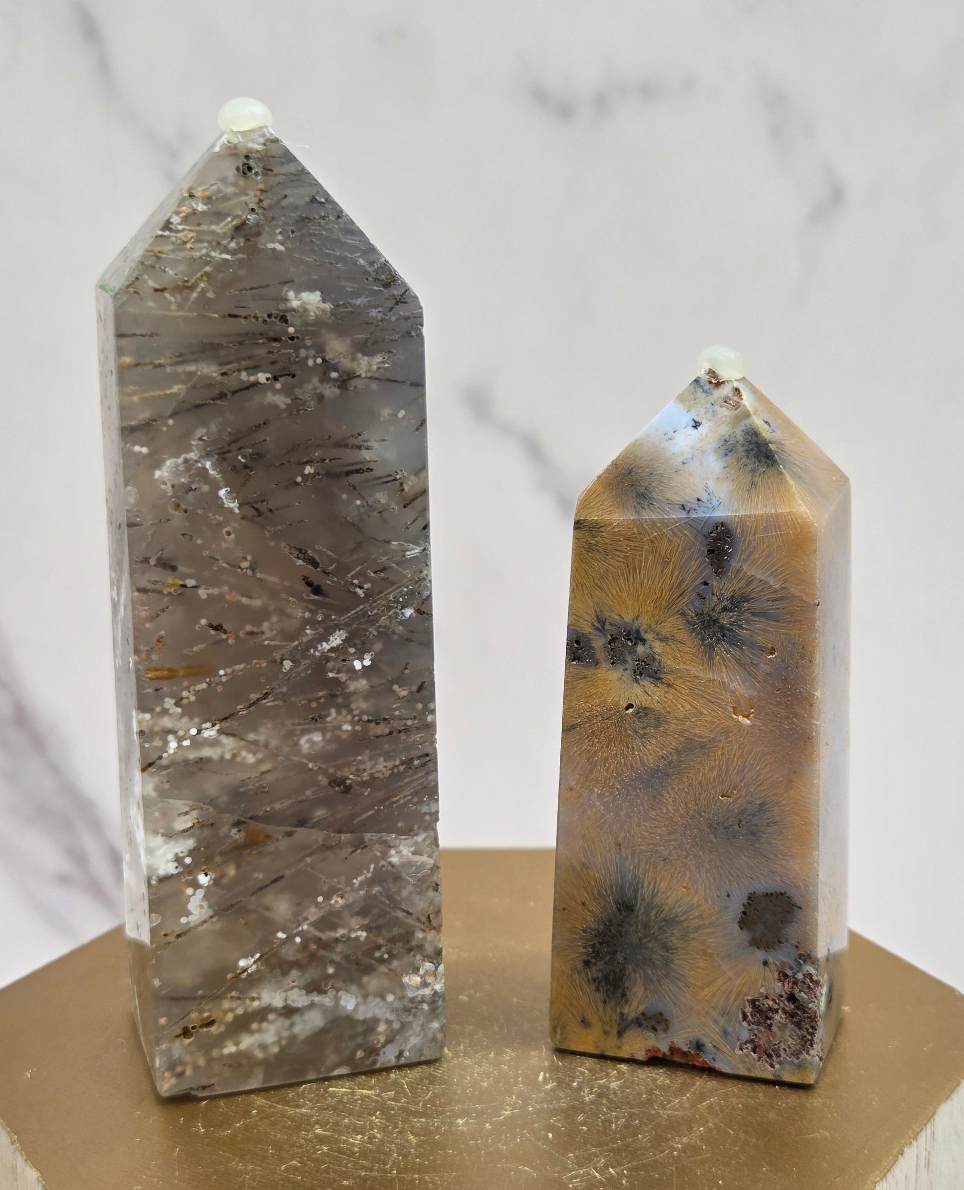 Two crystal points with inclusions on a wooden stand against a white background