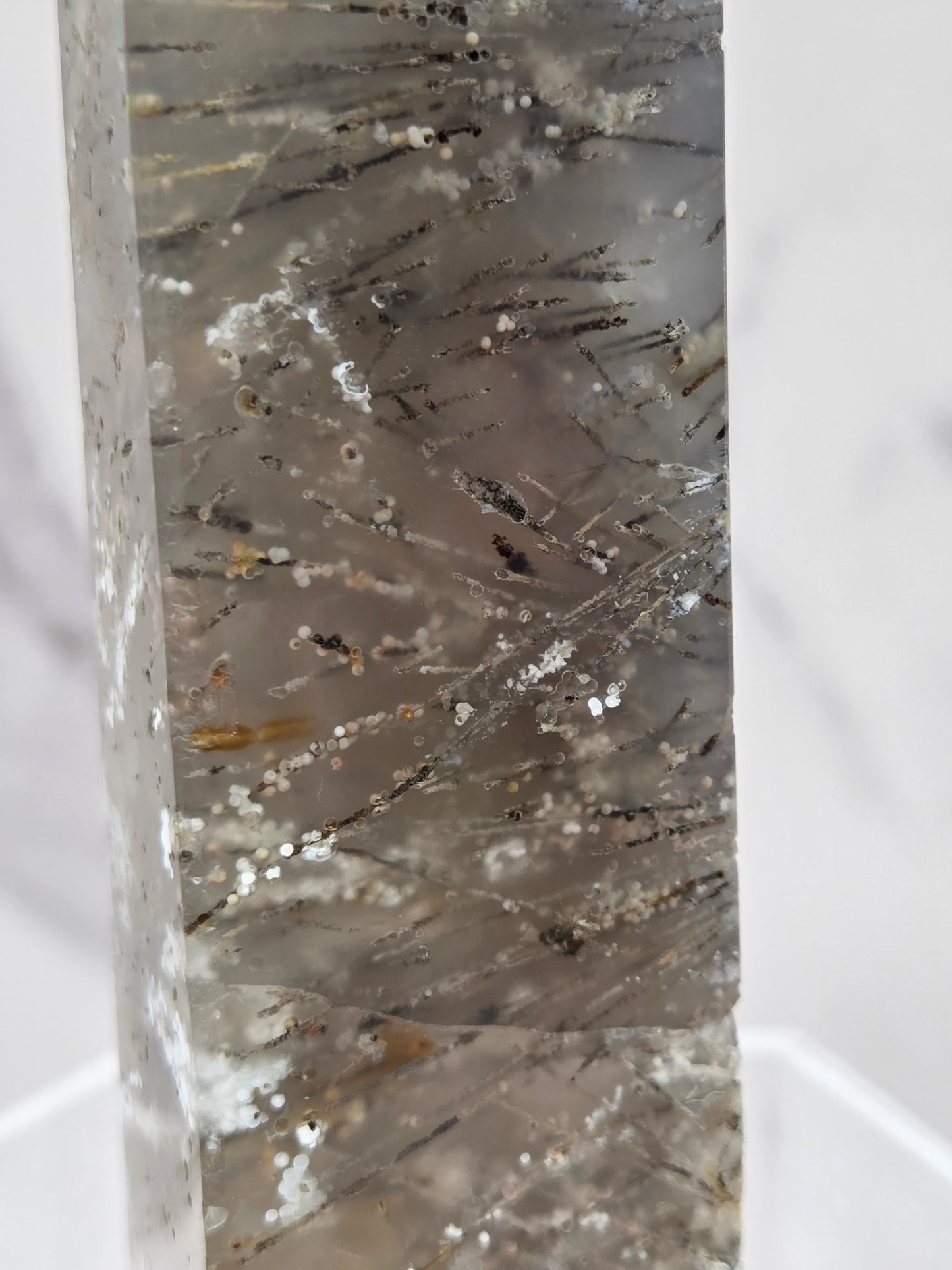 Close-up of a crystal point with inclusions against a white background