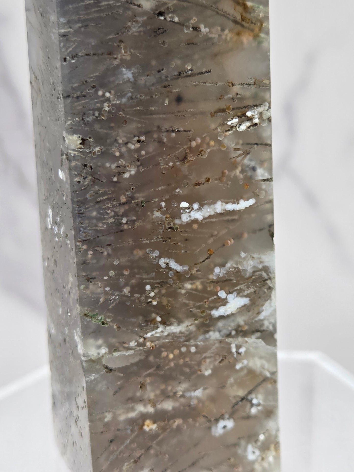 Close-up of a crystal point with inclusions against a white background