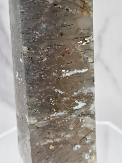 Close-up of a crystal point with inclusions against a white background