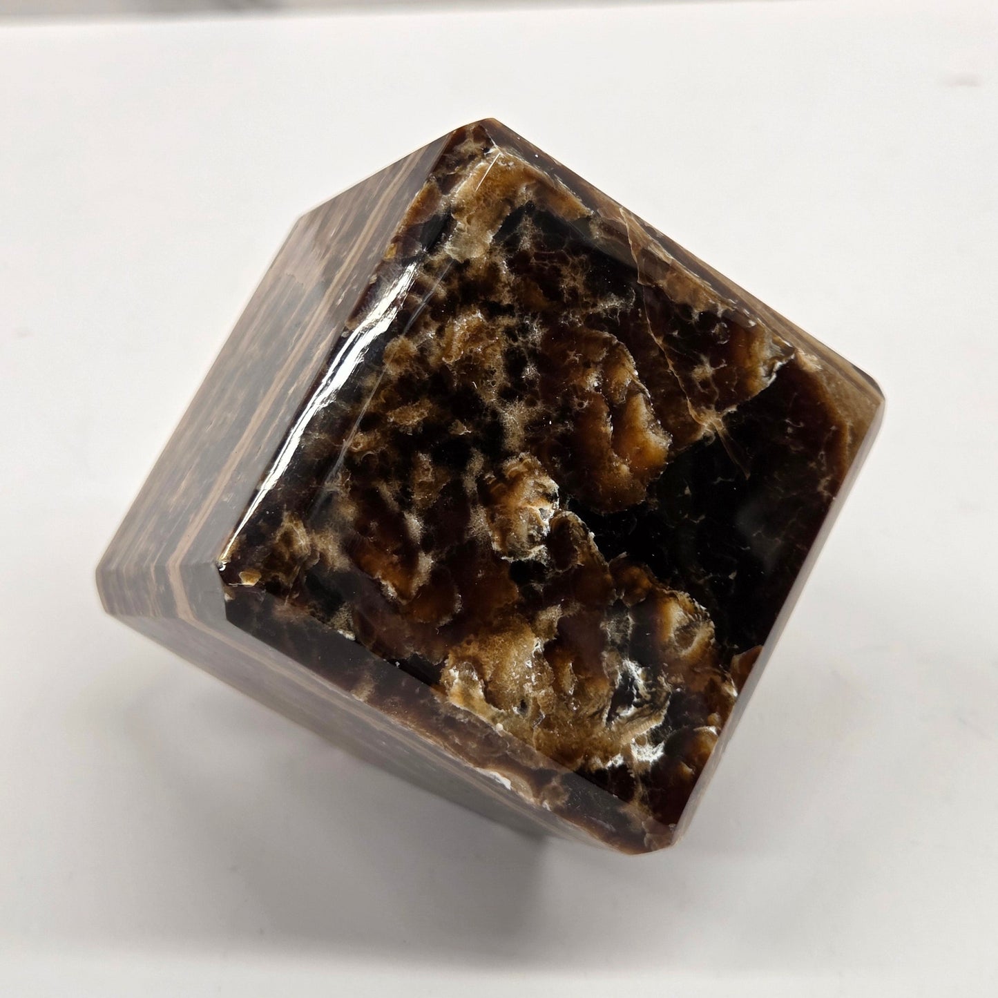 Marbled chocolate calcite cube on a white background