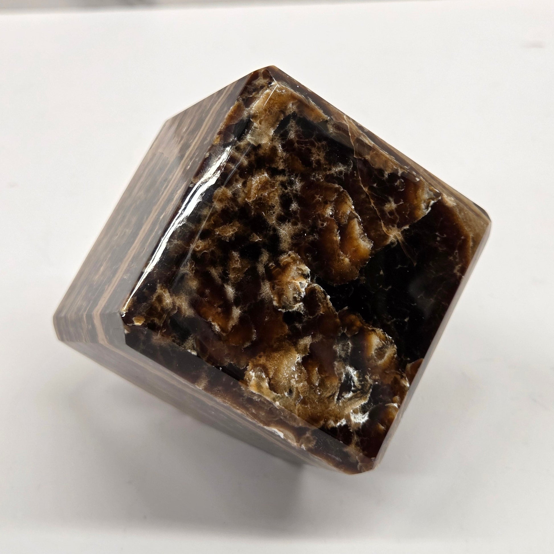 Marbled chocolate calcite cube on a white background