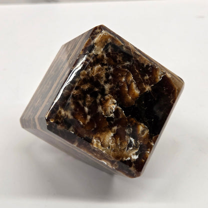 Marbled chocolate calcite cube on a white background