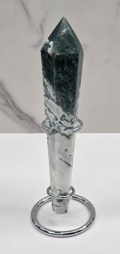 Moss agate wand carving in a silver stand against a white background