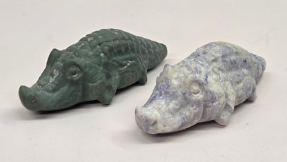 Two stone carvings of crocodiles on a white surface