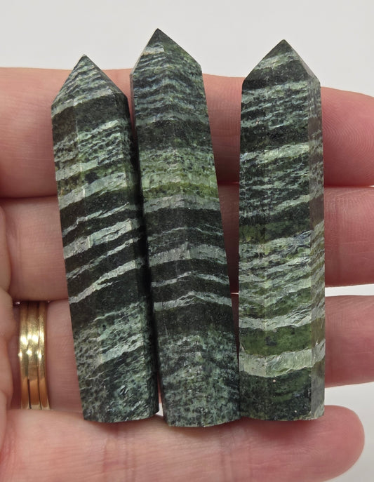 Three green striped small towers held in a hand against a white background