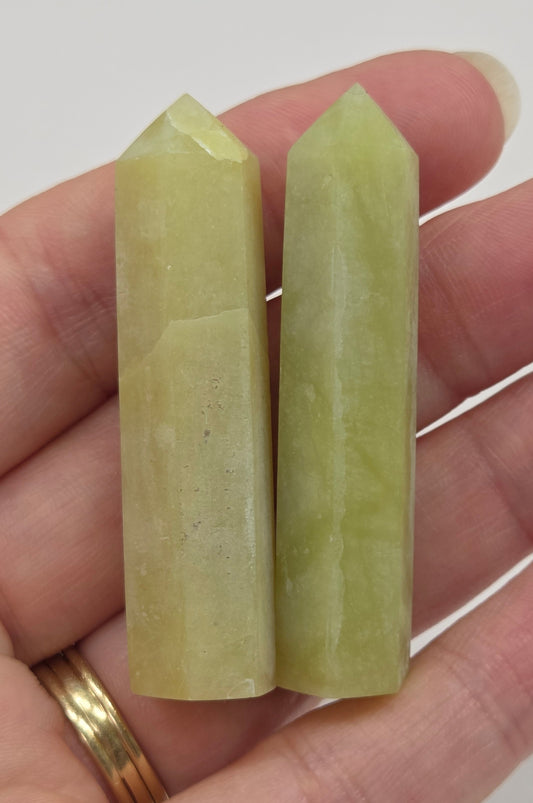 Two green lime jade towers held in a hand against a white background