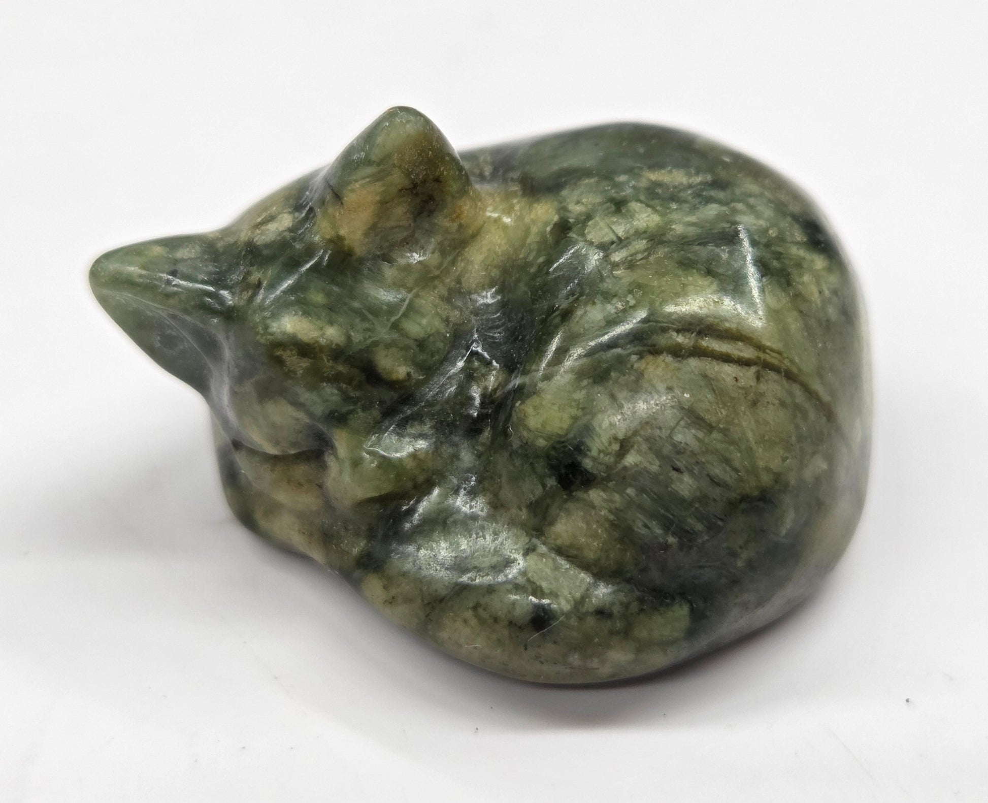 Green stone carving of a cat on a white background