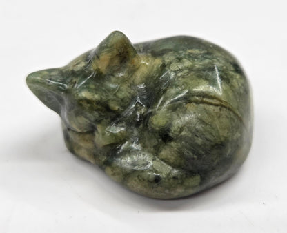 Green stone carving of a cat on a white background