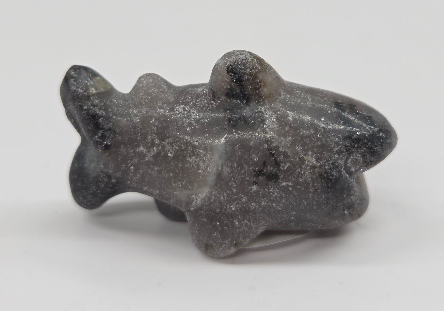 Grey and black colored crystal shark carving on a white background