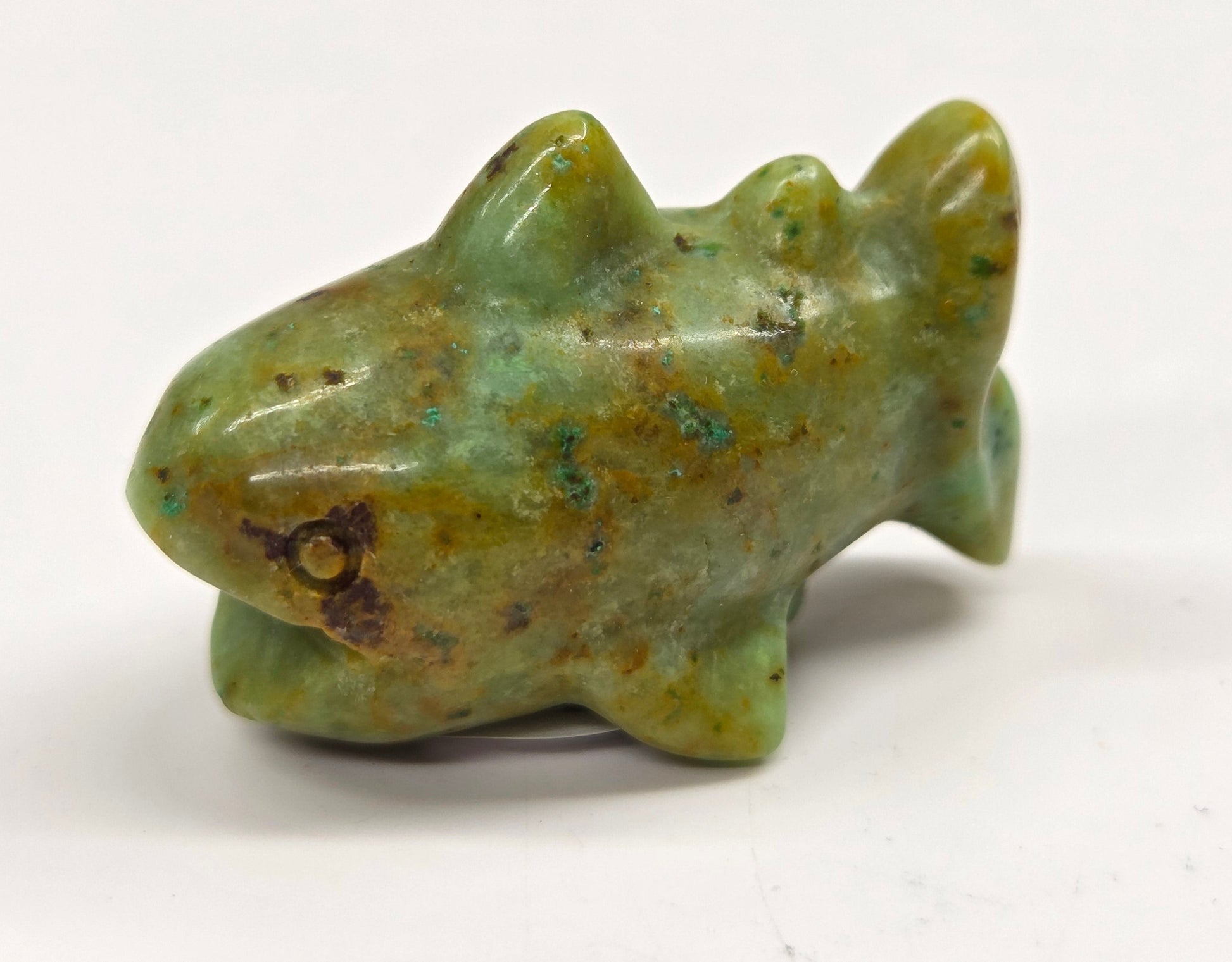 Yellow and greenish colored crystal shark carving on a white background