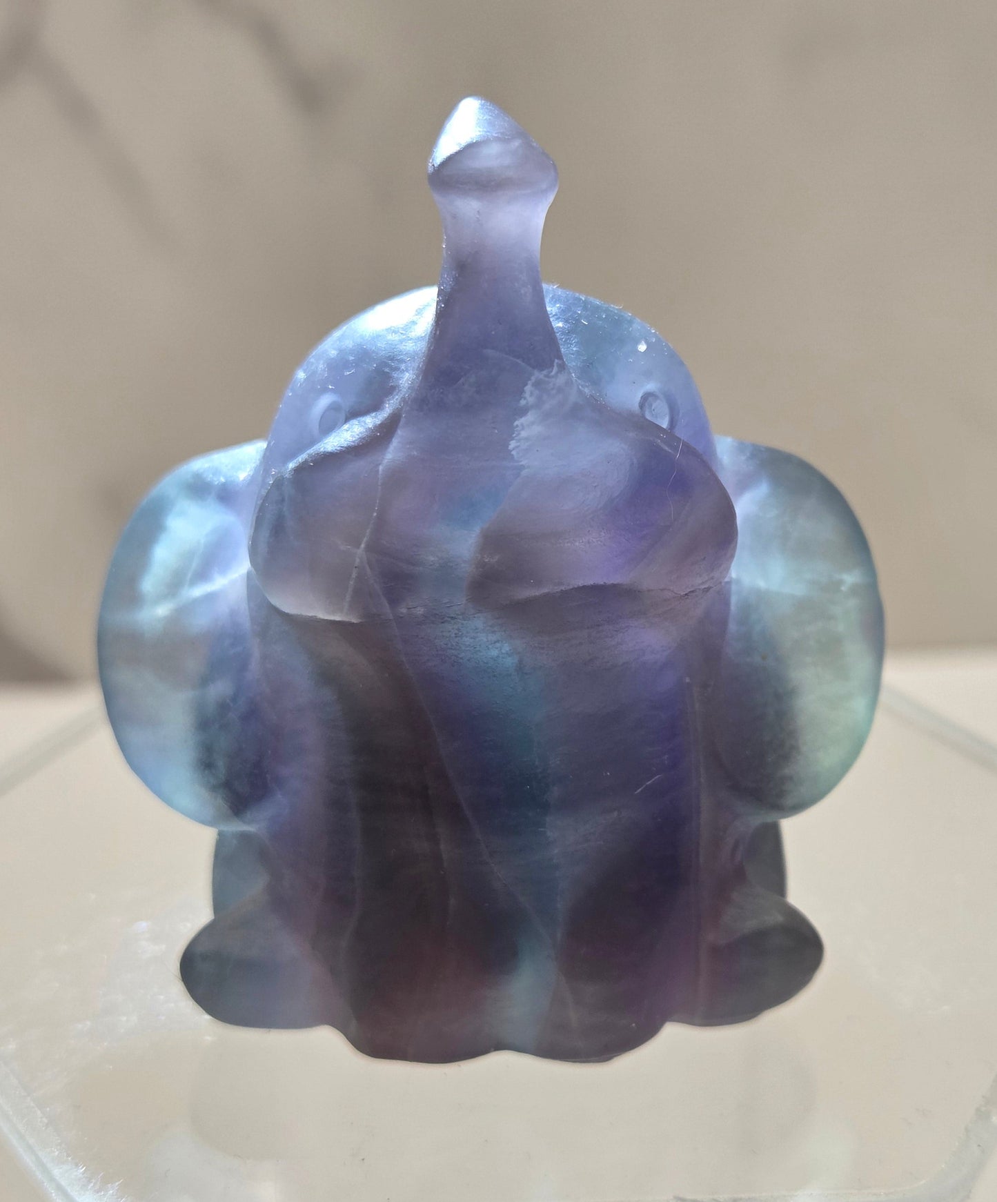 Decorative Fluorite sculpture of an elephant being backlit on a white background