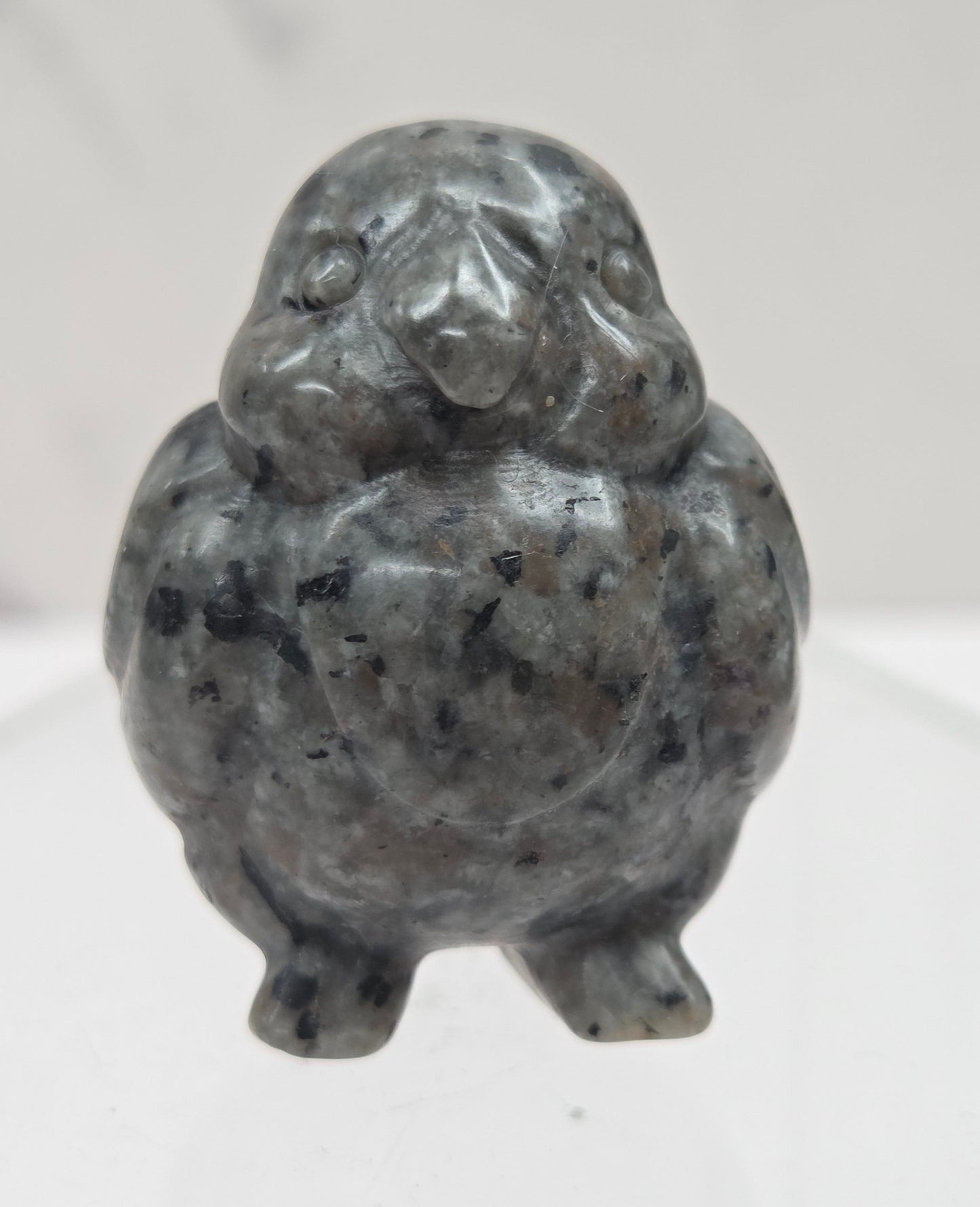 Decorative bird carving made of Yooperlite on a white background
