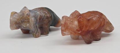 Two stone triceratops carvings on a white background