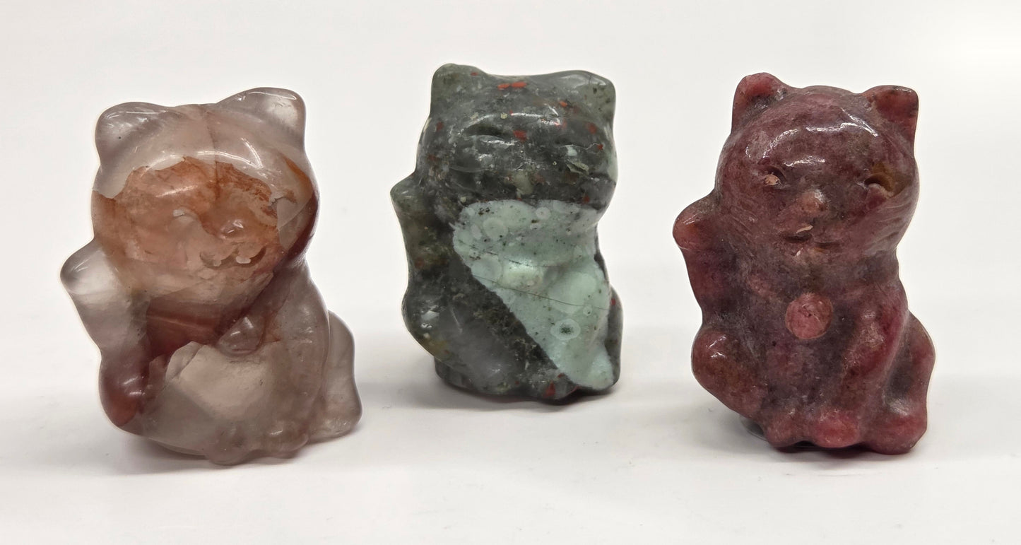 Three stone-carved cat figurines on a white background