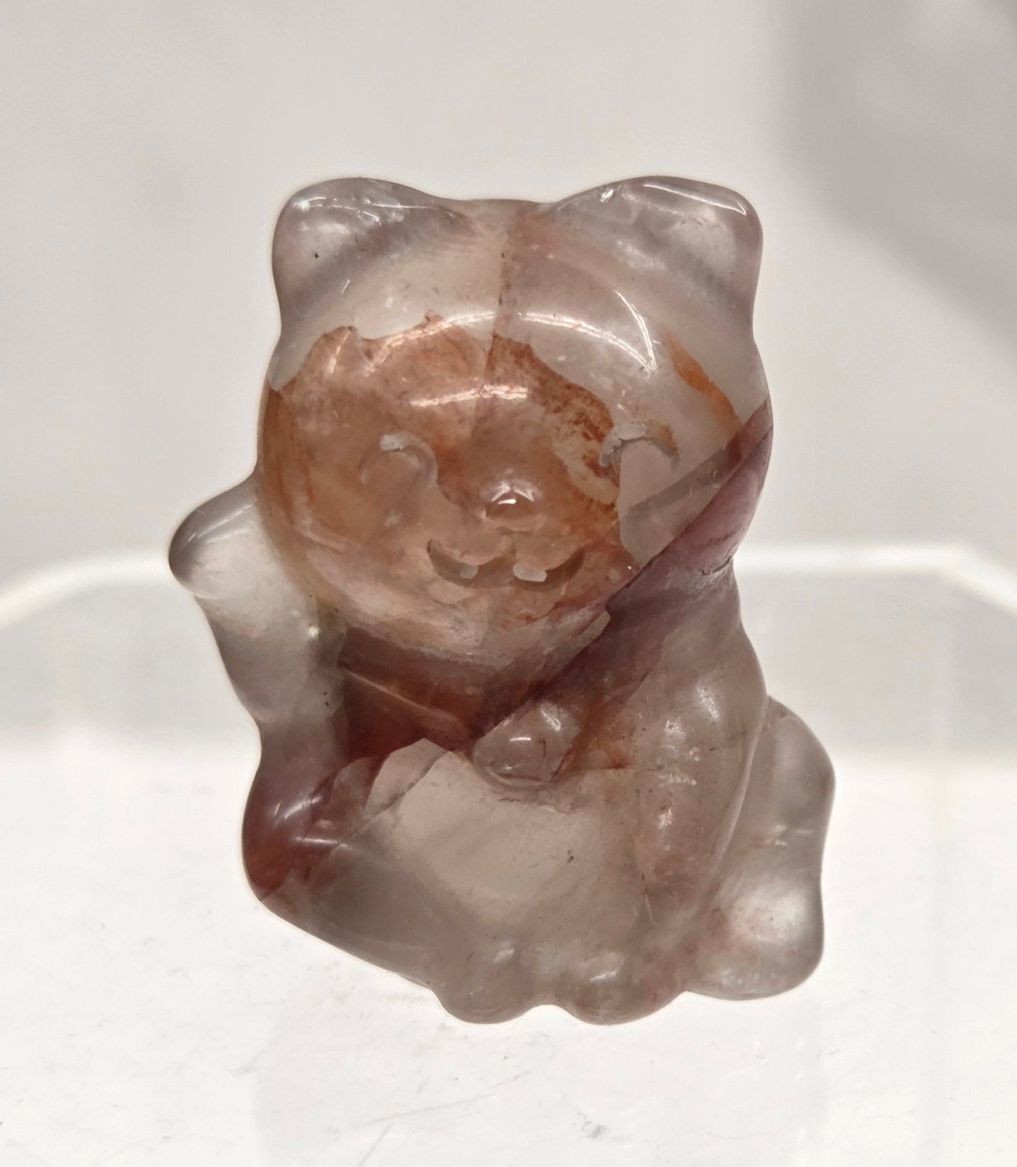 Small fire quartz cat carving on a light gray background
