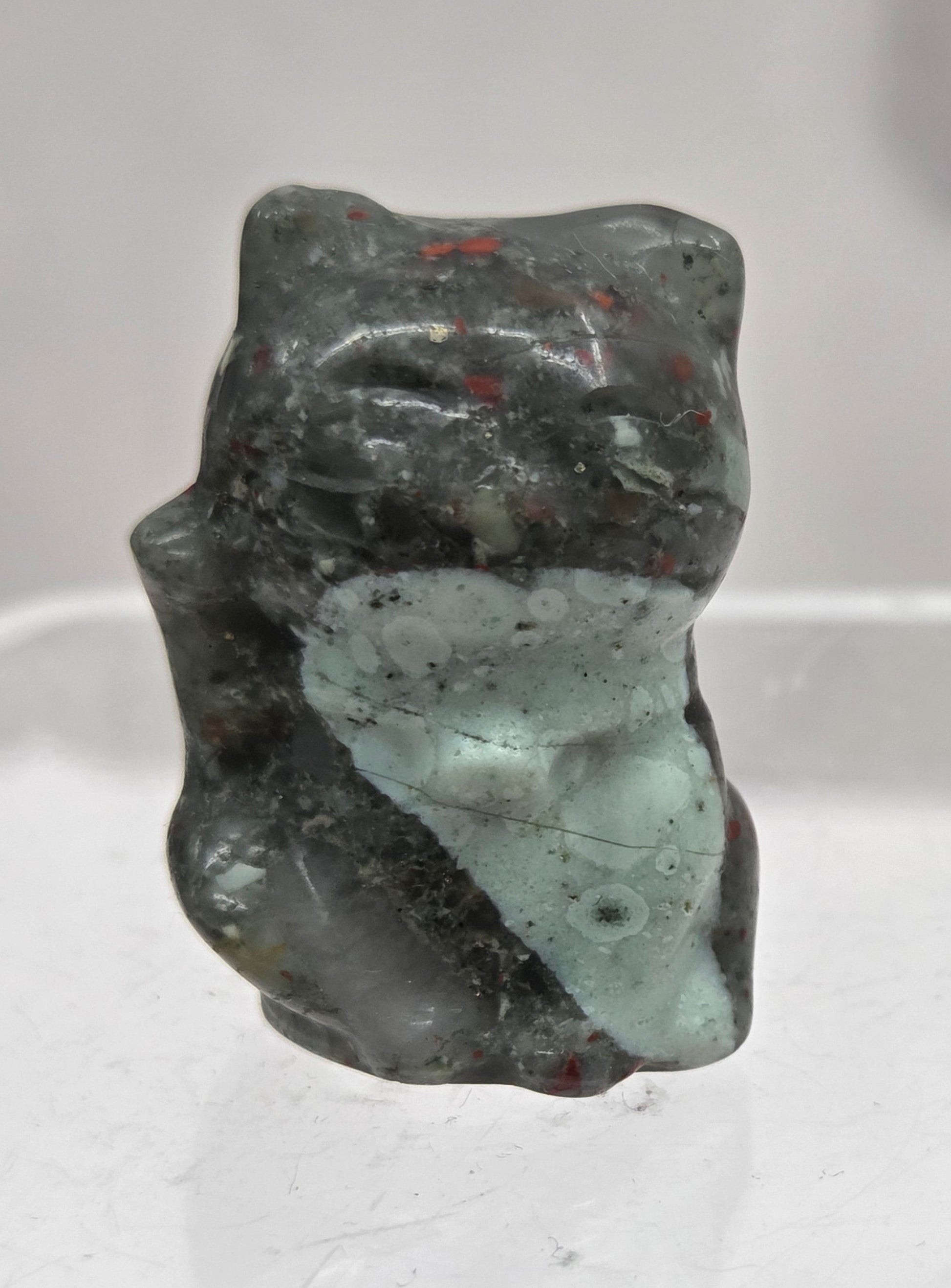 Small african bloodstone cat carving on a light gray background