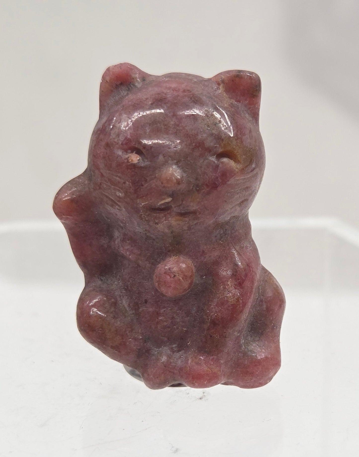 Small strawberry quartz cat carving on a light gray background