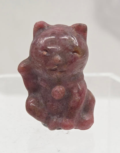 Small strawberry quartz cat carving on a light gray background