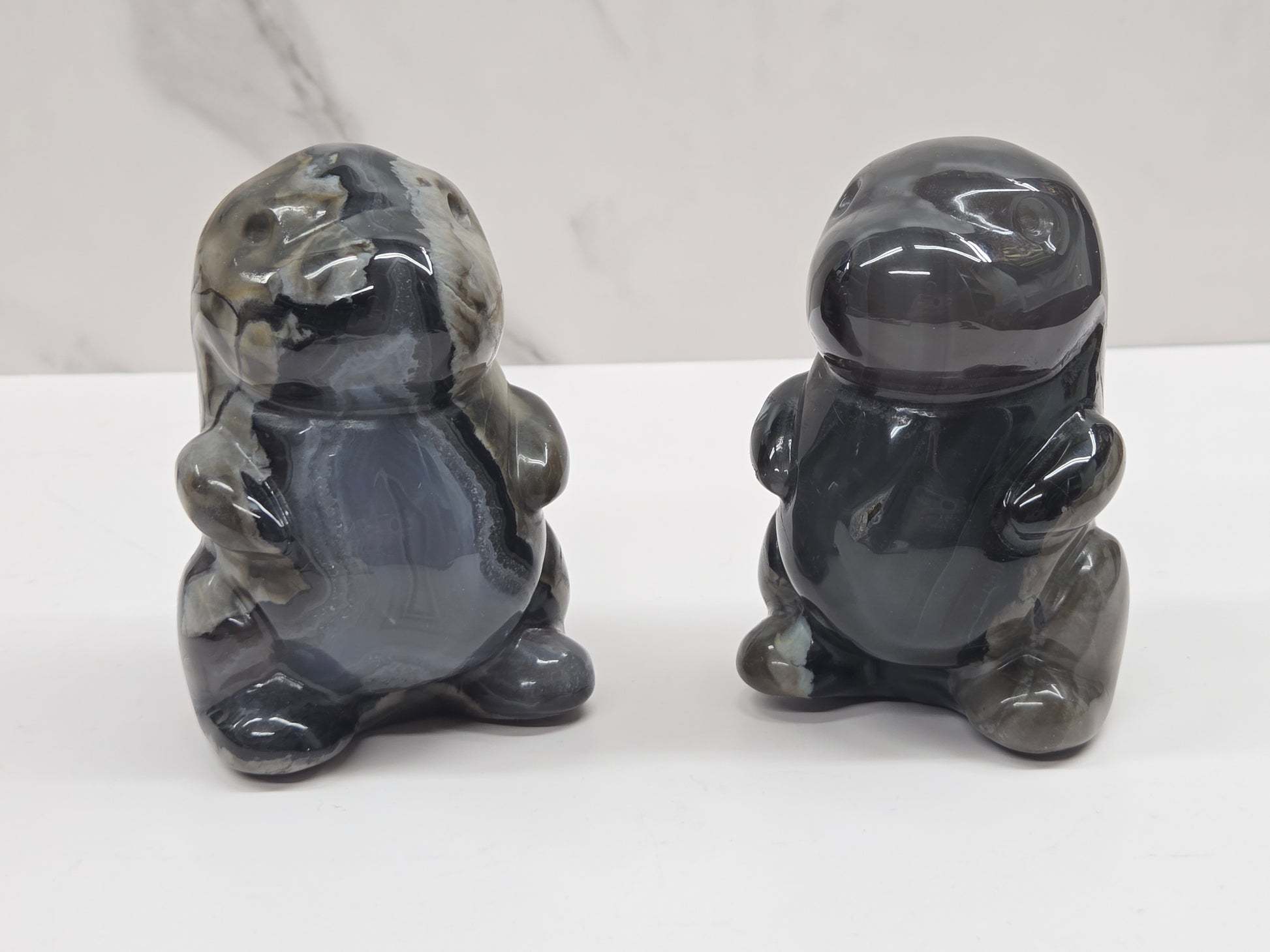 Two Volcano Agate cute dinosaur like carvings on a white background